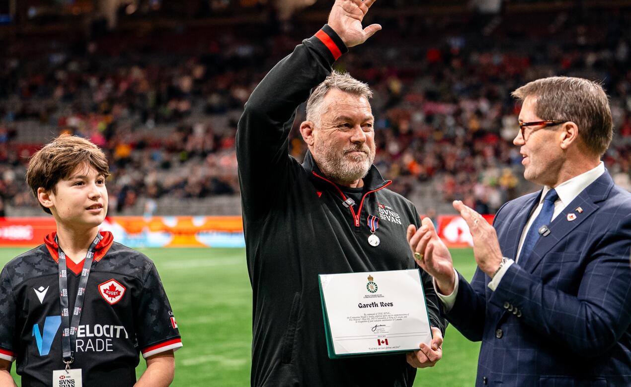 Alumnus Gareth Rees receives an award at center field