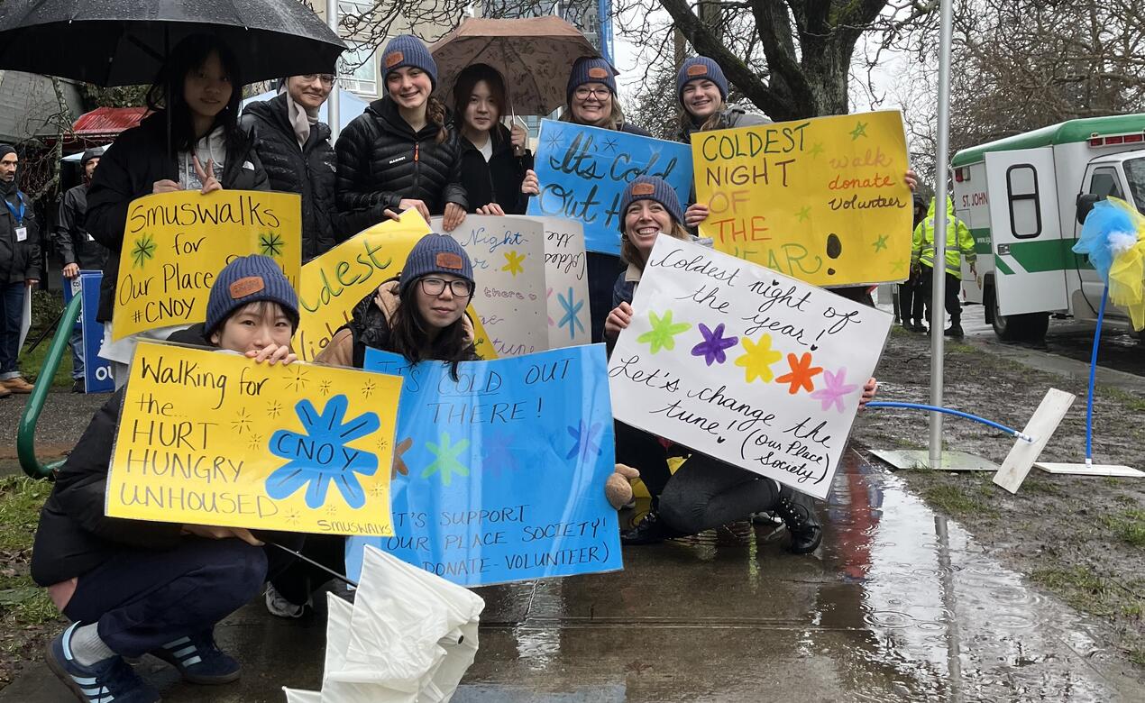 SMUS students brave the rain and hold up their Coldest Night of the Year posters ahead of their 5-km walk