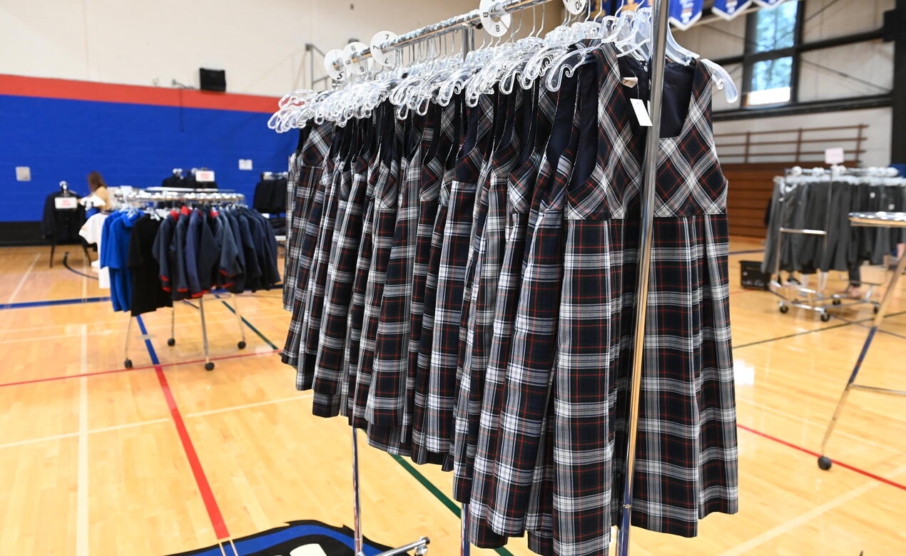 A rack of uniform jumpers hangs in the school gym. 