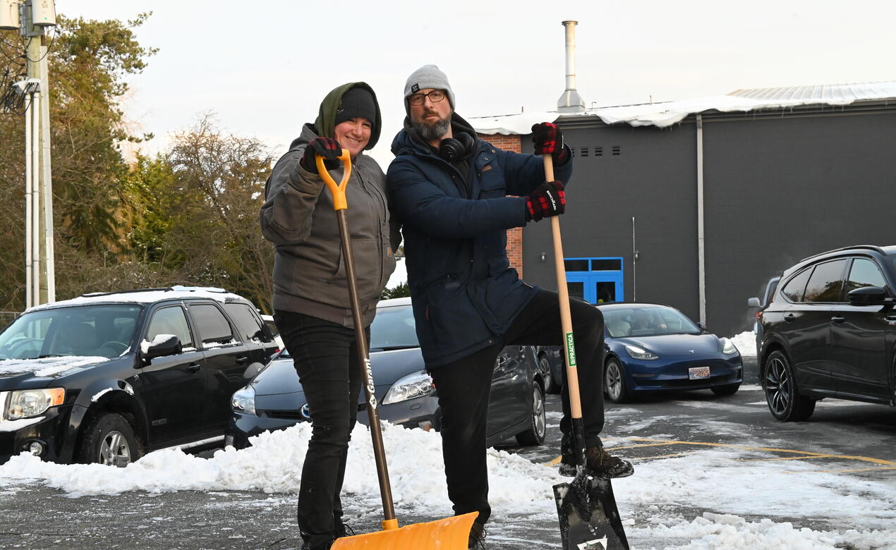 Cathy Beglau and Morgan Besant pose in the middle of clearing snow on the pathway