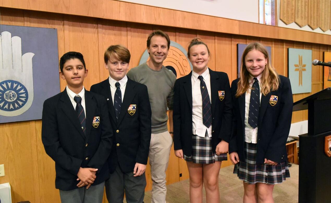 Speaker Dr. Jared Horvath poses with four middle school students after a keynote lecture.