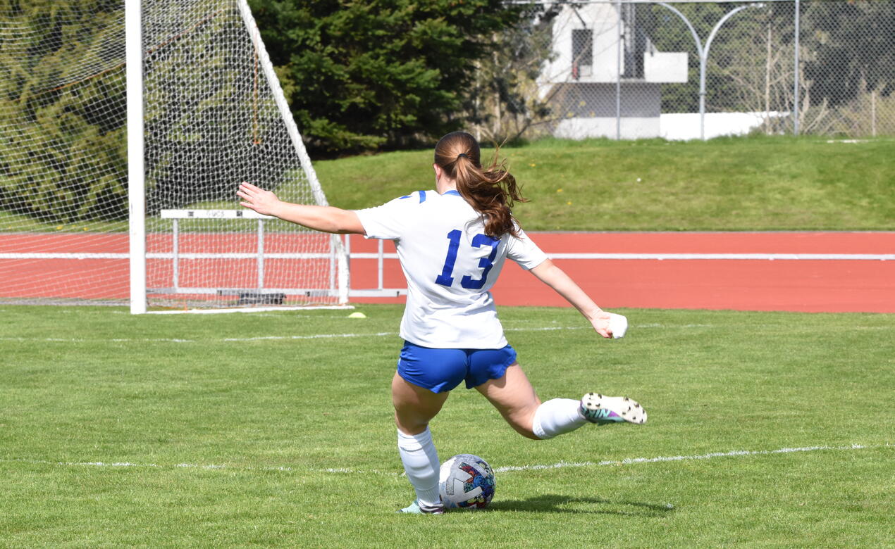 Mackenna Brown kicks a soccer ball across the field. 