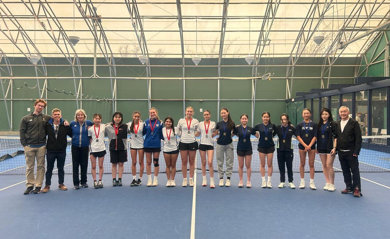 Senior Tennis Team stands in a line with silver medals around their neck.