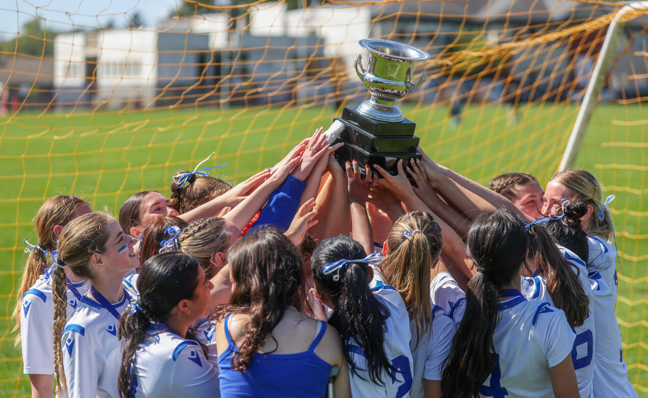 Senior Girls Soccer Team all hoist the ISAA Trophy together