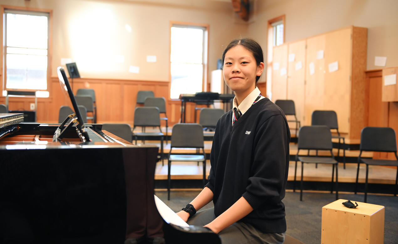Emily Wu portrait at a piano in the choral room