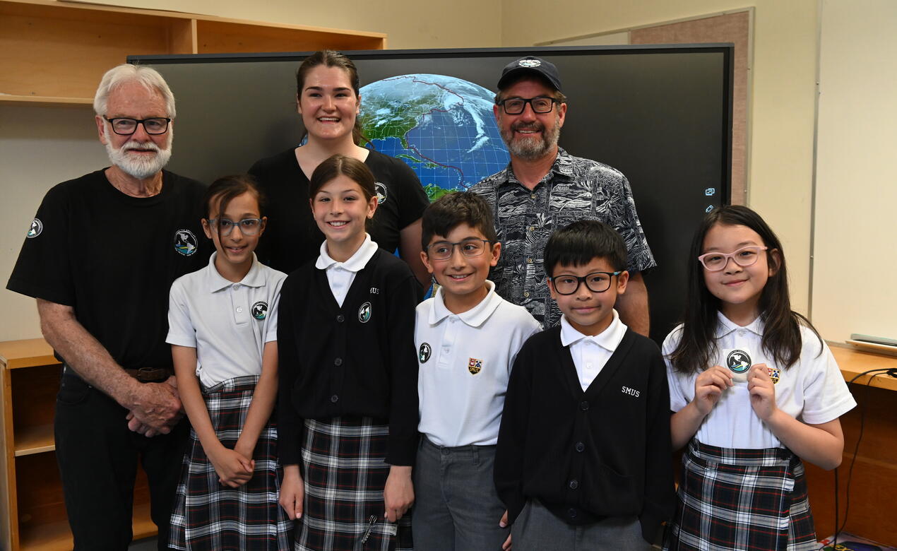 Grade 4 students pose with members of the visiting One Ocean crew