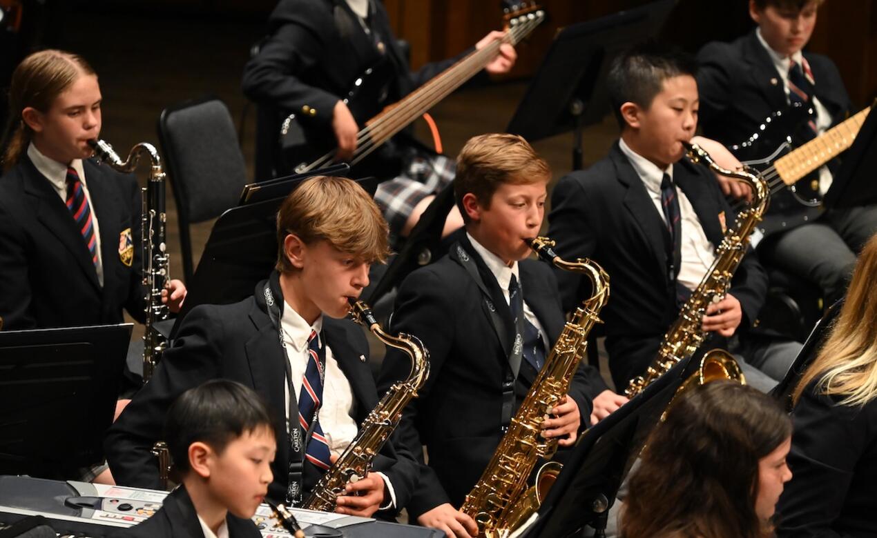 Saxophone players in the Middle School band concentrate while performing on stage. 