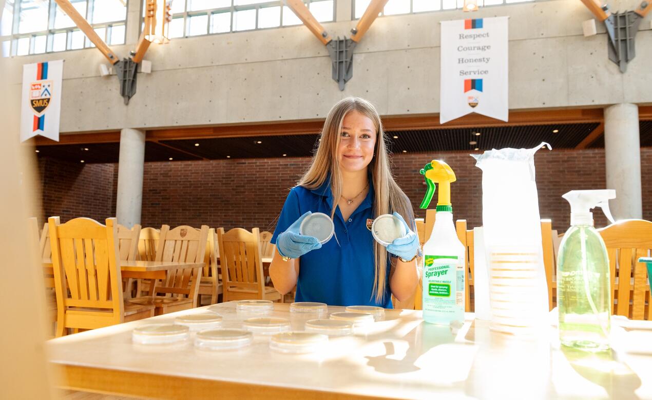 Fiona Davison holds up two petri dishes as she test the surfaces in Graves Hall