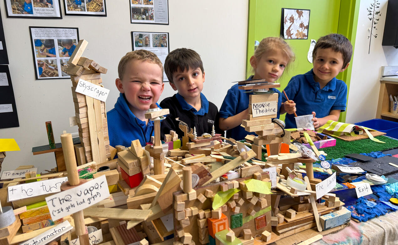Junior Kindergarten students stand behind their class-created city scape.
