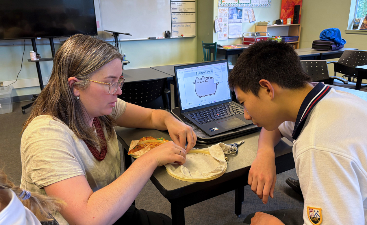Amy Stark showing embroidery technique to a student