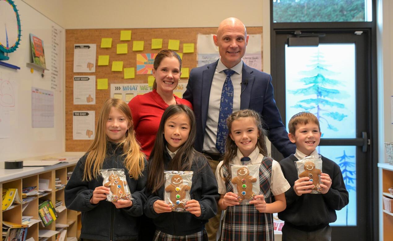 Members of Grade 1 stand with gingerbread cookies alongside Dr. Jeff Aitken and his wife Mariana