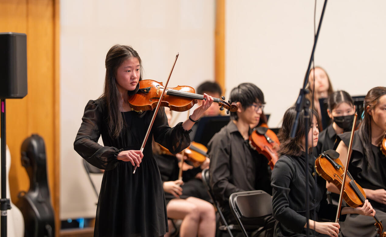 Michaela Yee stands for a violin solo during a performance.