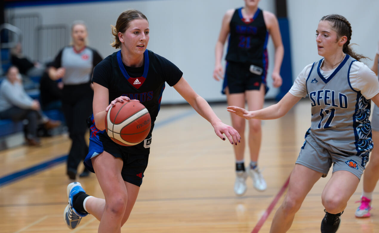 Mya Beare dribbles in basketball past a Mark Isfeld player.
