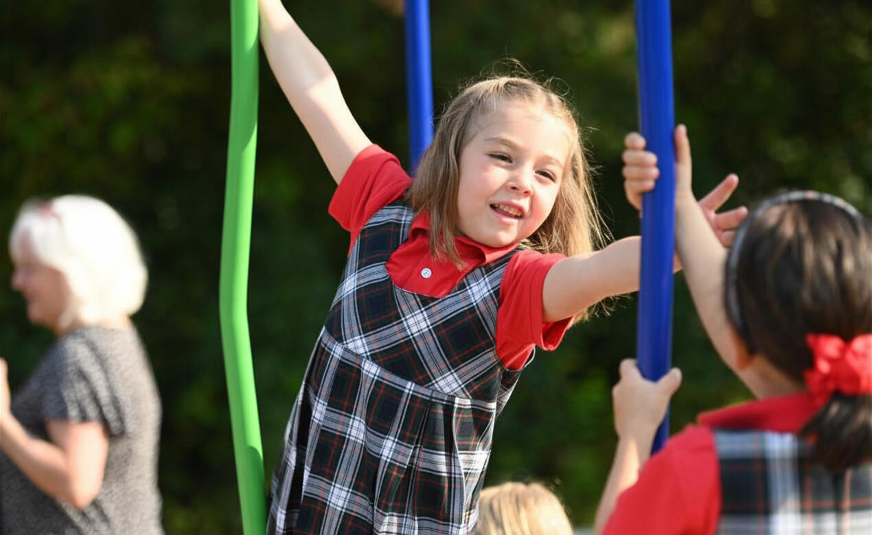 Kindergarten student Maeve reaches for a bar on the playround. 