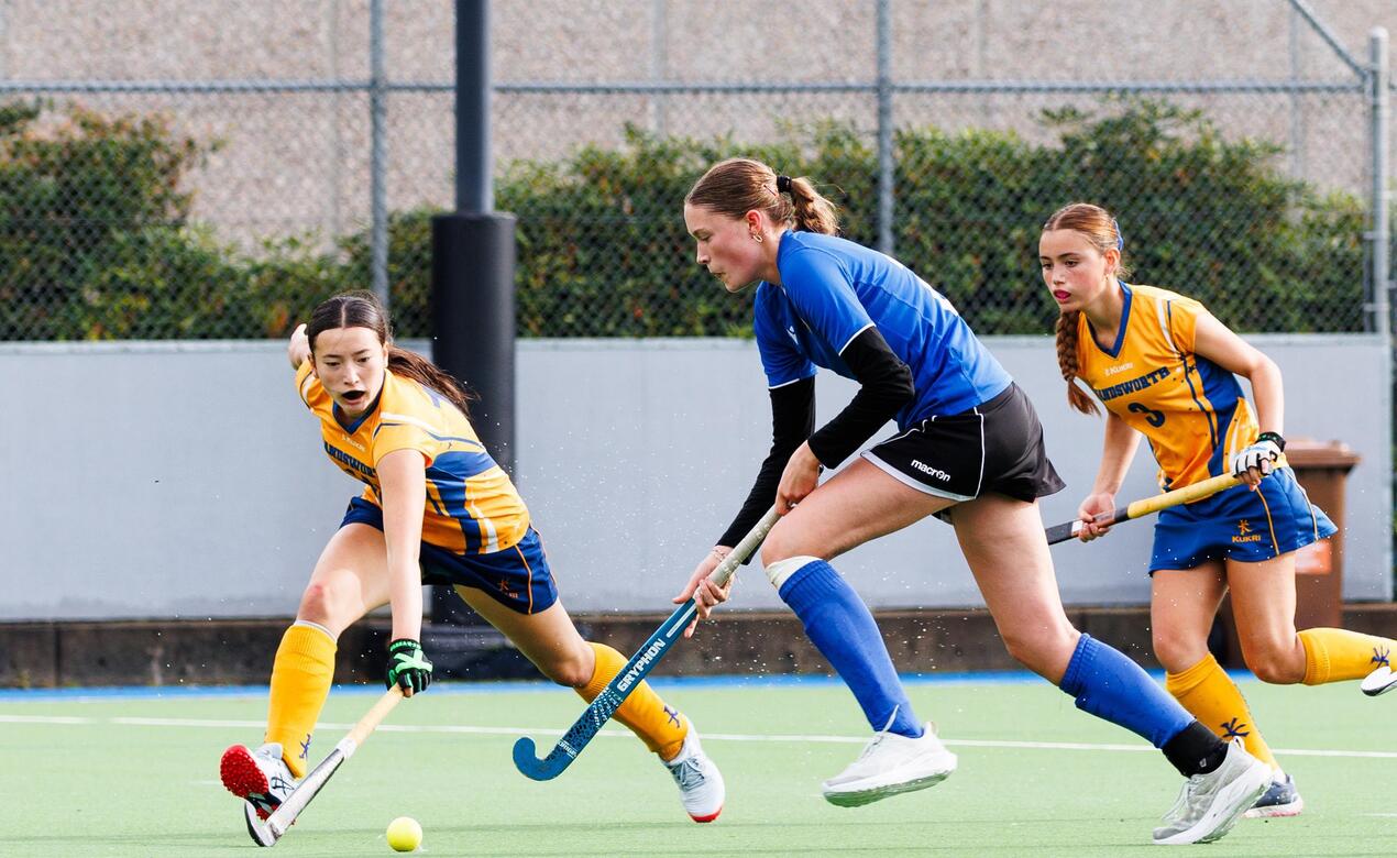 Elspeth Rodgers dribbles past Handsworth defenders in field hockey competition. 