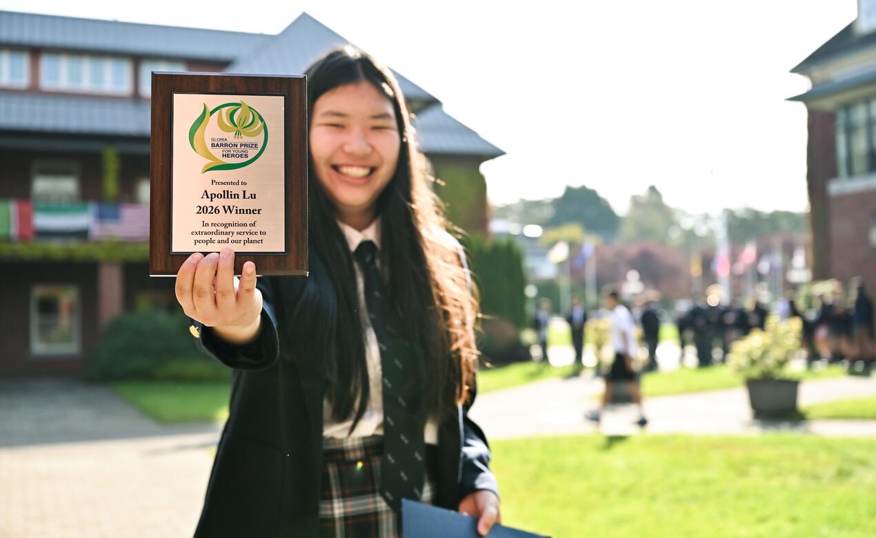 Apollin Lu holds out a plaque she won. 