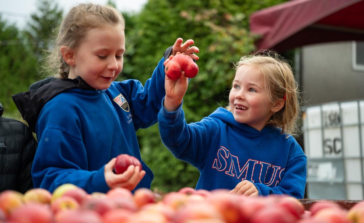 Two students share a laugh over a strangely-shaped apple. 