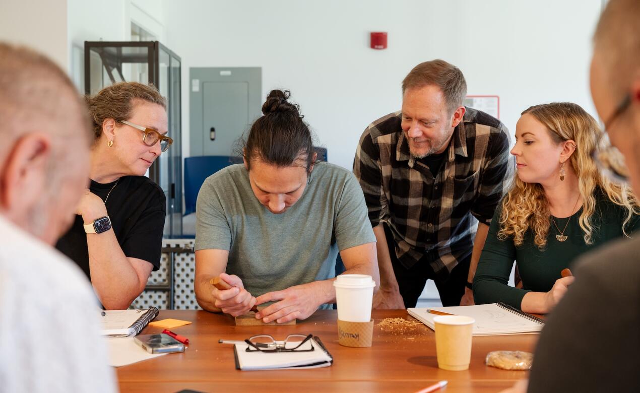 Staff Art teachers look on as Indigenous artist Dylan Thomas carves a cedar plank