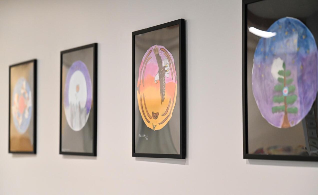 Four framed drawings of spindle whorl inspired art made by Grade 5s hangs on a wall