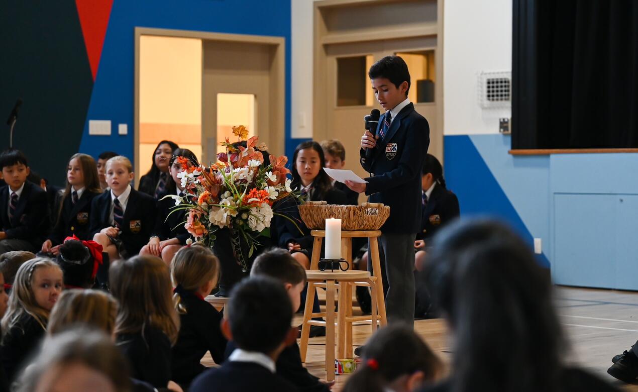 A Grade 5 student reads his speech while holding the microphone. 