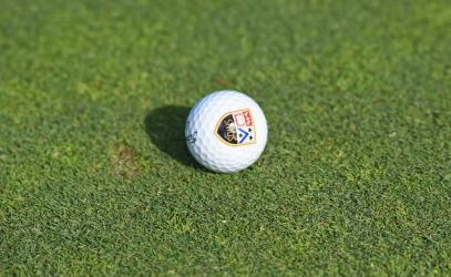A golf ball with the St. Michaels University School crest sits on a golf green