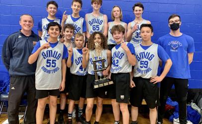 Middle School boys basketball team members pose with a trophy