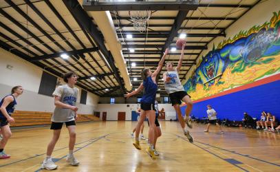 A student jumps in the air with the basketball at the hoop