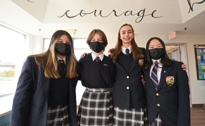 Four Grade 8 students pose together in front of a sign that reads Courage