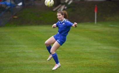 A student athlete jumps in the air to head the soccer ball