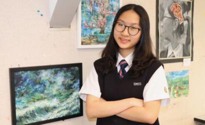 A photo, taken by the Saanich News, of student artist Giang Tran posing with her artwork.