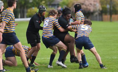 A Senior Boys Rugby player pushes through a crowd of opposing players