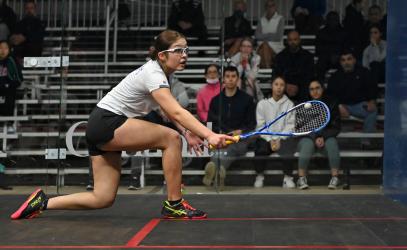 A squash player reaches to hit the ball
