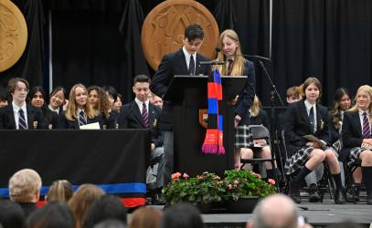 Grade 8 students Matthew and Samantha stand on stage together during the Closing Ceremony and deliver a speech in front of a large crowd.