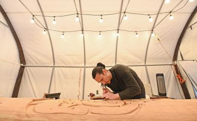 Indigenous Scholar Dylan Thomas works on carving the SMUS welcome post