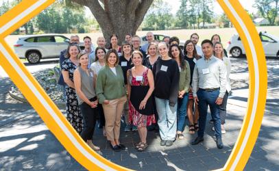 A group of new SMUS faculty and staff stand in front of a tree