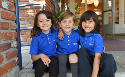A group of Junior Kindergarten students smile on the steps of the Junior School