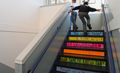 Middle School students run up a staircase adorned with colourful and multilingual messaging