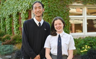 Senior School students Steven and Bo stand in front of the ivy-covered School House building