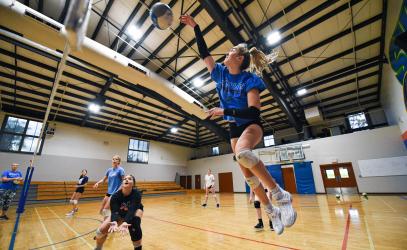 A Senior School volleyball player is airborne as she spikes the ball, while her teammates watch