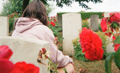 Senior School student Clara Curry, with her back to the camera, sits in front of a gravestone for Capt. R.V. Harvey