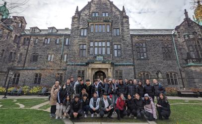 A group of Grade 12 students pose in front of Trinity College at the University of Toronto during a university tour.