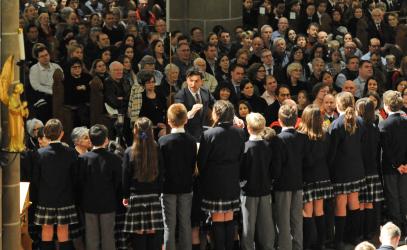 Choir teacher Duncan Frater conducts a group of SMUS students in Christ Church Cathedral, as a large crowd of families watch