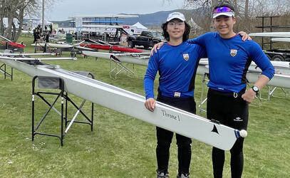 Two rowers pose next to the Throne 1 boat at the Maple Bay Regatta