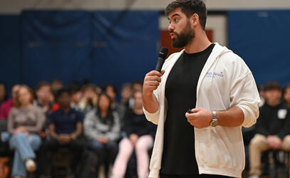 Laurent Duvernay-Tardif holds a microphone and speaks in front of a crowd of SMUS students