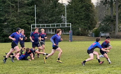 A student tackles an opposing player as others run on