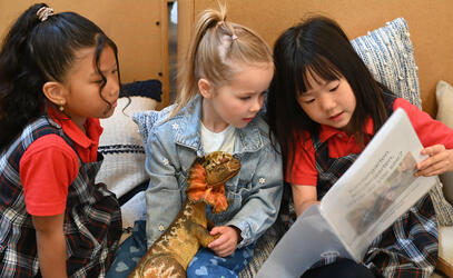 2 students look on as 1 student reads from an orientation booklet
