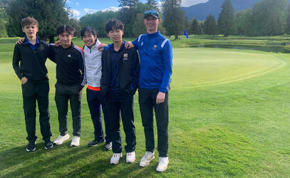 5 players stand on the edge of the green