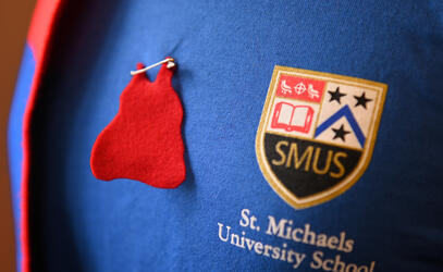 A red dress pin appears next to a SMUS logo on a t-shirt