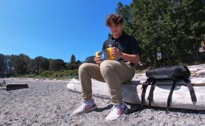 Liam Pope Lau sitting on a log on a beach