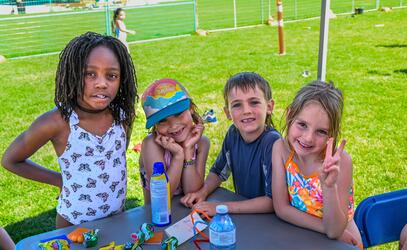 Four day campers smiling at the camera with a watertight happening around them